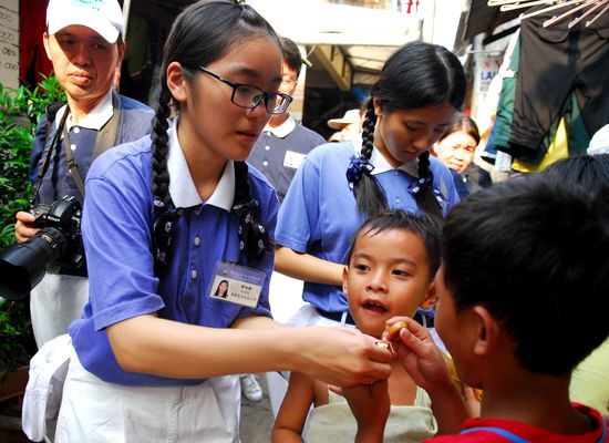 Chen Yi Chen (21), salah seorang Tzu Ching Taiwan sedang membantu membuka permen untuk anak-anak di Pademangan Barat.  