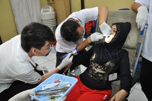 Anggota TIMA dengan hati-hati menangani pasien gigi di acara bakti sosial kesehatan. 
