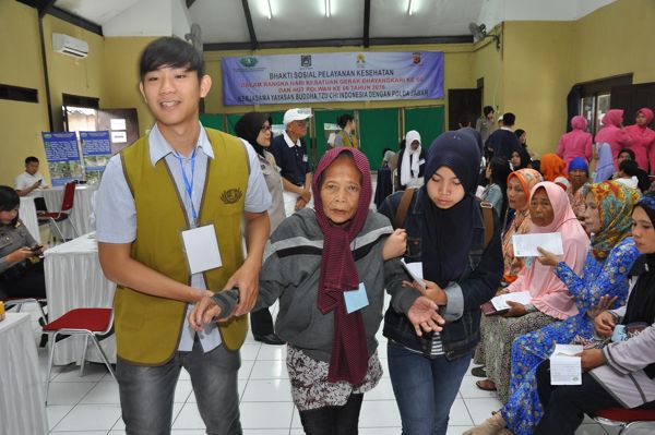 Relawan Tzu Chi bekerja sama dengan warga yang hadir membantu pasien berjalan untuk menadapatkan pengobatan.